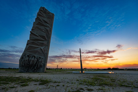 Wroclaw, Poland - August 23 2023: Beautiful big cross on top of Oporowskie hill with graves around next to big monument to the Soldiers of the Polish Army at beautiful cloudy sunsetのeditorial素材