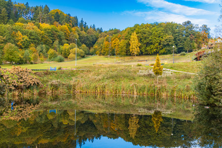 Polanica-Zdroj, Poland - October 21 2023: Small pond with silent water beautifully reflecting hills and trees around next to Goralka toboggan runのeditorial素材