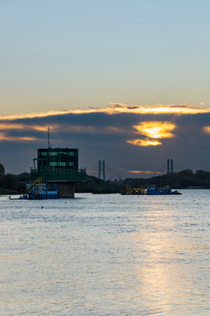 Warsaw, Poland - October 15 2023: Beautiful cloudy sunrise with golden clouds and rising sun over long Vistula river seen from Pinsk Flotilla boulevard at cold morningのeditorial素材