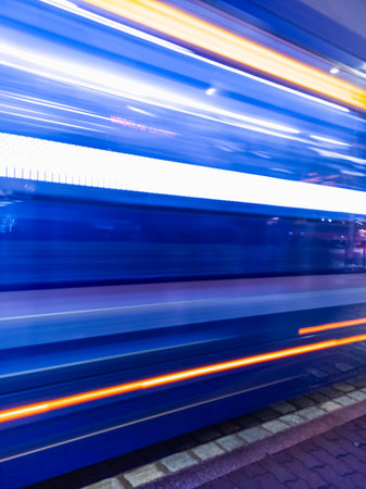 Wroclaw, Poland - December 7 2023: Beautiful and colorfully glowing light stripes of tram and cars at tram station next to main railway station with big and glowing neon lamp on topのeditorial素材