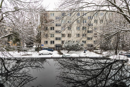 Wroclaw, Poland - December 2 2023: Beautiful winter view through the window to city street between high old trees and cars covered with fresh white snow reflecting in small black plastic boxのeditorial素材