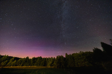 Beautiful dark night sky full of stars and flying Perseids in front of shades of aurora and milky...