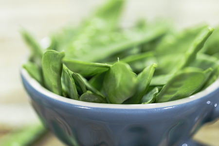 Sugar snap peas on rustic background and blue cup