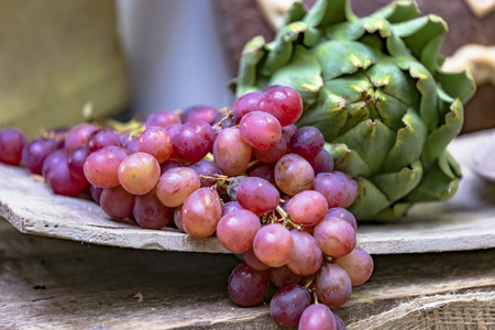 Market stall with red grapes and artichokes on a rustic wooden board