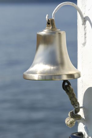 ship metal bell with rope on a white hookの写真素材