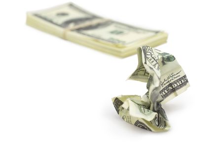 crumpled false dollar bill in the foreground and batch of dollars tied with rubber band in the backgroundの写真素材