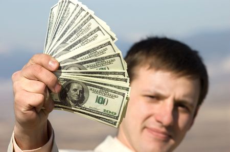 man holding dolllars in hand, face is defocused