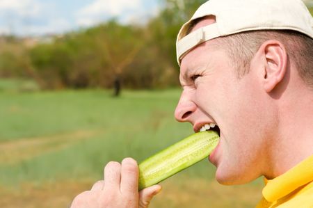face of man in profile biting cucumberの写真素材