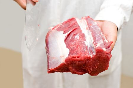 piece of fresh beef and knife in butchers handsの写真素材