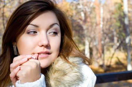 young brunette european girl looks sideways her thumb in mouthの写真素材