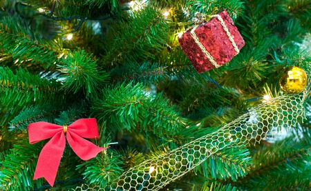 fragment of christmas tree with red bow, gift box and gilt ballの写真素材