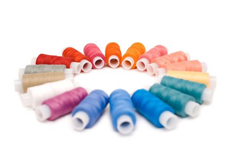 circle of coloured reels of thread against white background, shallow DOF