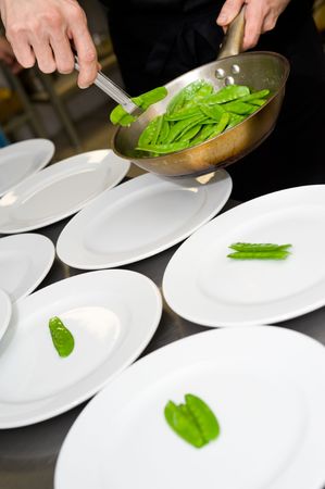 restaurant cooking, laying out of green pea pods on platesの写真素材