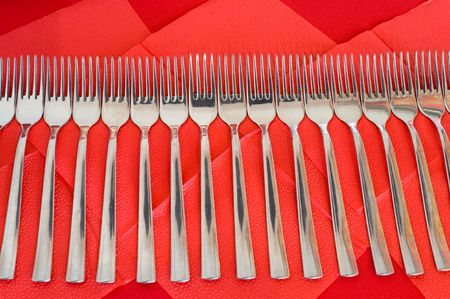 a line of steel forks on red paper napkins