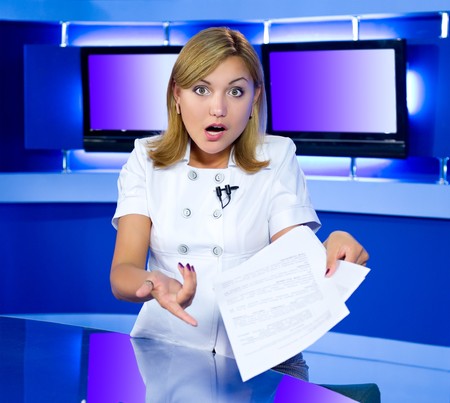 a television anchorwoman at a studio is shocked by news she has in her handsの写真素材