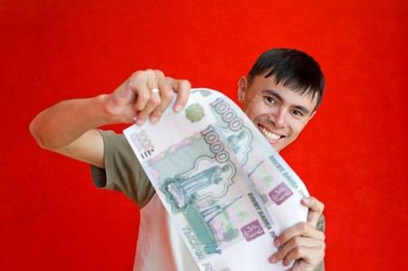 young man holds enlarged false ruble billsの写真素材