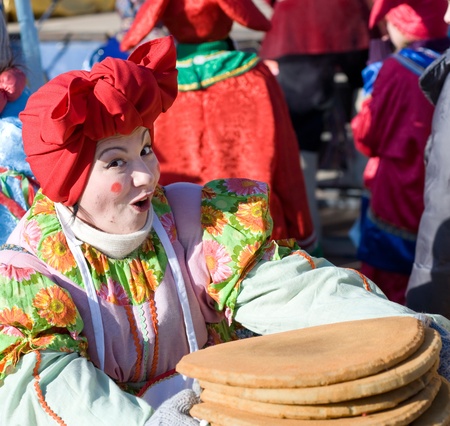 ULAN-UDE, RUSSIA - FEBRUARY 14: A woman in russian folk costume offers pancakes on the last day of the Pancake festival, February, 14, 2010, Ulan-Ude, Russia.のeditorial素材