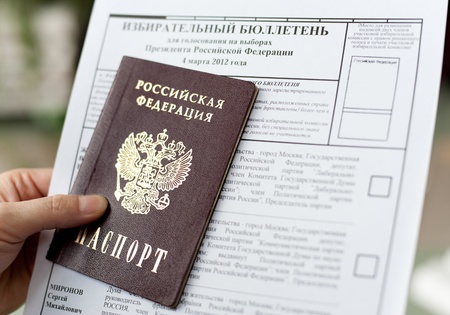 a hand holds a passport and a ballot for voting at the presidential election of Russian Federation,...