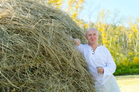 a caucasian man in a white shirt rests against a haystackの写真素材