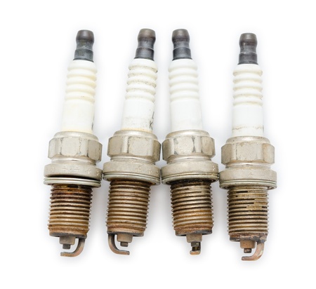 four old spark plugs, over white background