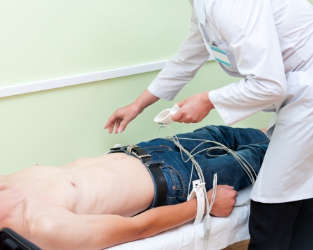 a doctor attaches sensors on a patient for taking his electrocardiogram