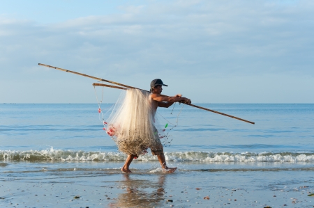 MUI NE, VIETNAM - FEBRUARY 27  An unidentified Vietnamese fisherman walks along the shore after fishing carrying his folded net, February 27, 2013 in Mui Ne, Phan Thiet, Vietnam のeditorial素材
