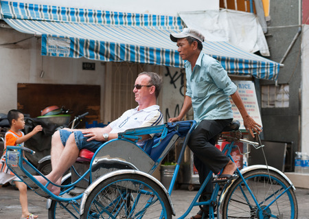 HO CHI MINH, VIETNAM - JULY 7, 2014: An unidentified cyclo driver carries a Caucasian tourist on Bui...