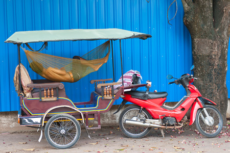 a Cambodian driver sleeps in hammock in his tuktukの写真素材