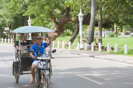 SIEM REAP, CAMBODIA - JUNE 28, 2014: An unidentified tuktuk driver drives Caucasian tourists in the street. The town is famous for its proximity to Angkor temples and night markets.のeditorial素材