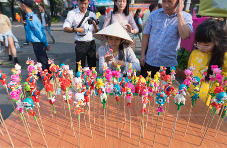 HO CHI MINH, VIETNAM - FEB 18, 2015: An unidentified young woman makes and sells plasticine toys on sticks on Tet Eve in the downtown. Tet is Lunar New Year and celebrated during four days in Vietnam.のeditorial素材