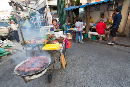 BANGKOK - MARCH 9, 2015: An unidentified local woman pushes her cart with bbq being grilled in the Khao San Road area, the center of the backpackers universe.のeditorial素材