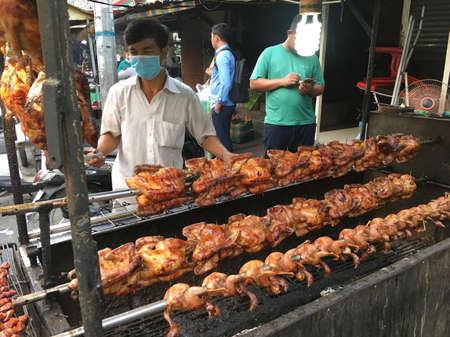 PHNOM PENH - MARCH 16, 2020: Unidentified street vendor cooks grilled meat at a food market in Phnom Penh, Cambodia.のeditorial素材