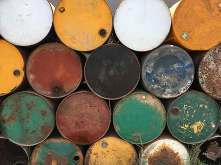 A pile of empty big rusty fuel metal barrels outdoors.