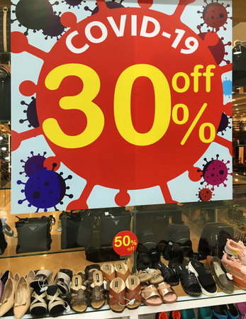 SIEM REAP, CAMBODIA - APRIL 30, 2020: Shoes on sale under an advertising poster Covid-19 30% off....