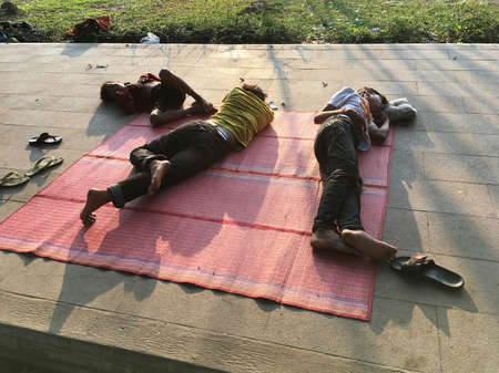 SIEM REAP, CAMBODIA - APRIL 22, 2020: Unidentified street food sellers sleep in the central city park after their late evening shift.のeditorial素材