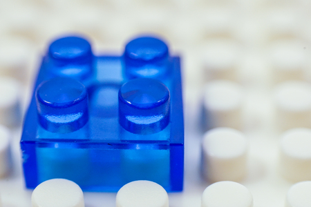 Tiny blue building block on a larger white blockの写真素材