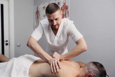 Sports massage. Massage therapist massaging shoulders of a male athleteの写真素材