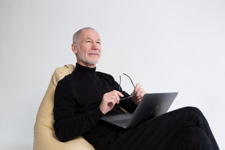 Senior old elderly grandfather man using laptop for freelance work, checking pension, working remotelyの写真素材