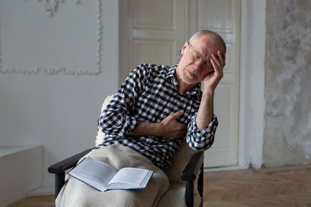 Senior male suffering from bad pain in his chest heart attack at home.の写真素材