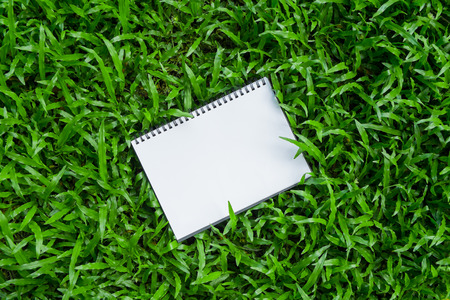 A rotated note book laying on grassの写真素材