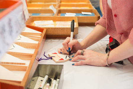 Unidentified woman drawing her wish on fox faces card, Fushimi Inari Shrine, Tokyo, Japanのeditorial素材