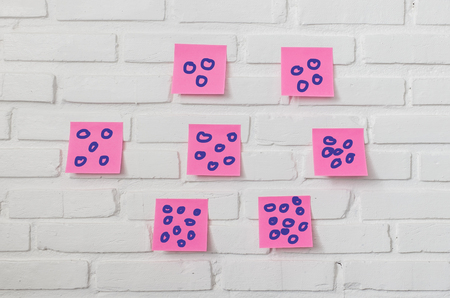 pink note paper stick on white brick wallの写真素材