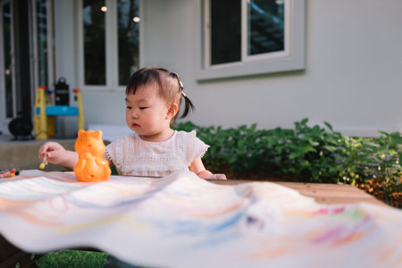 Asian Baby girl coloring on paper in the gardenの写真素材
