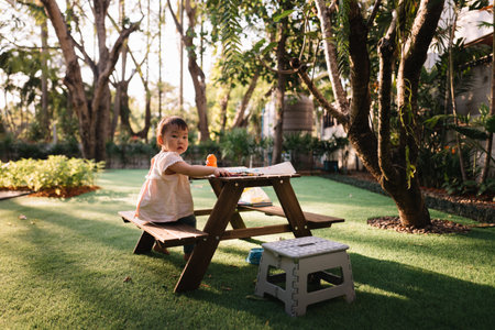 Asian Baby girl coloring on paper in the gardenの写真素材