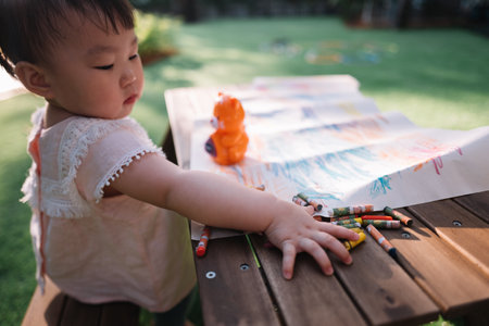 Asian Baby girl coloring on paper in the gardenの写真素材