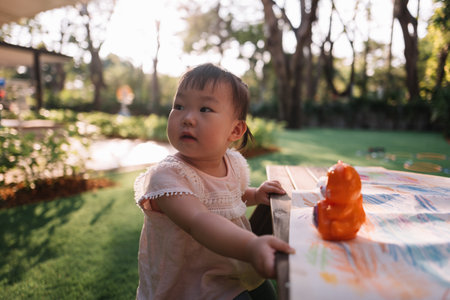 Asian Baby girl coloring on paper in the garden