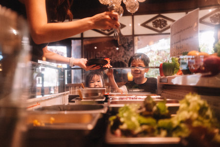 Asian woman picking food for her children, focus at kidsの写真素材
