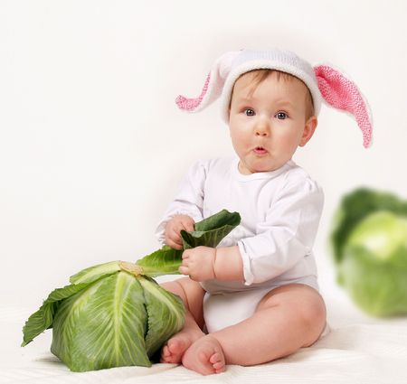 Sitting child in a hat with cabbage.の写真素材