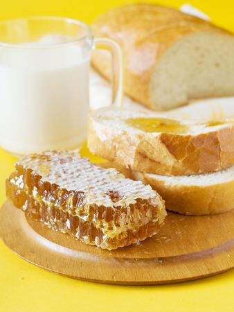 Honey, bread and milk for breakfast. All on a yellow backgroundの写真素材