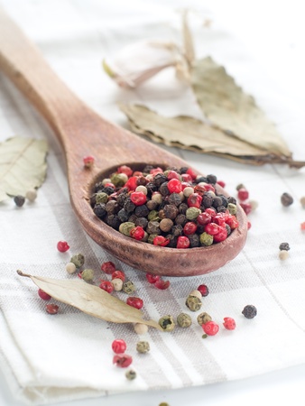 Peppercorns in wooden spoon with garlic on backgroundの写真素材